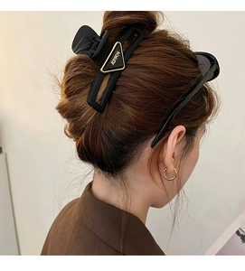 Detailed back view of a black matte triangle hair claw with gold POWER lettering logo