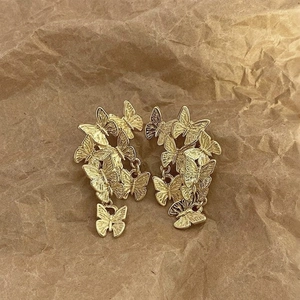 Golden butterfly drop earrings with engraved texture on brown textured paper background