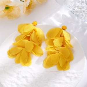Detail of yellow chiffon flower earrings with beaded studs on a decorative white plate