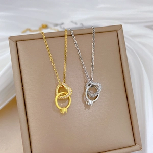 Dettaglio di ciondoli a cuore e anello intrecciati con zirconi lucenti in oro e argento