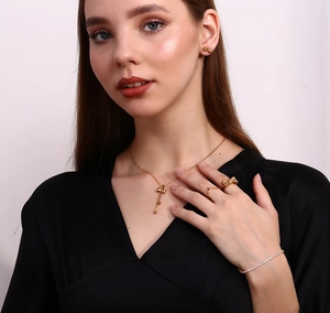 Close-up of golden bow jewelry set including necklace, earrings, and ring on a model