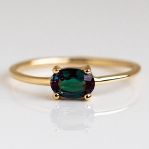 Detailed view of oval cut peacock zircon ring with gold plating and four-prong setting