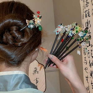 Detail showing a model wearing the wooden hair stick with elegant floral tassels