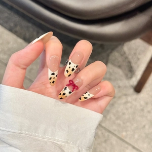 Handmade almond press-on nails with French cow print and 3D red bow accent