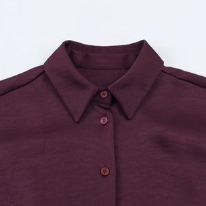 Detailed close-up of dark purple satin shirt collar and tonal buttons texture