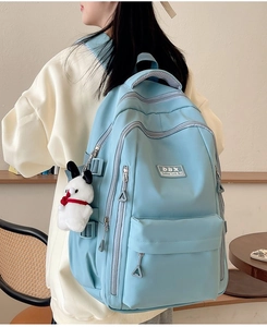 Detail view of sky blue ergonomic backpack with side pocket and cute plush pendant charm