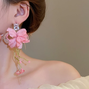 Close-up of pink fabric flower earrings with sparkling crystals and long beaded tassels