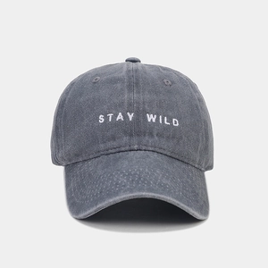 Dettaglio del cappellino da baseball grigio lavato con ricamo bianco STAY WILD