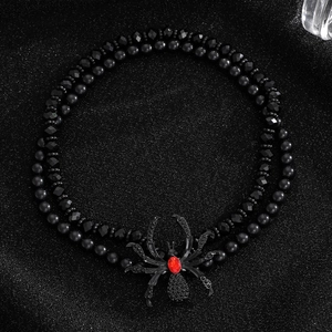 Detailed view of double-layer black beaded necklace with a red rhinestone spider pendant