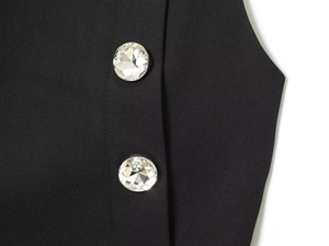 Detailed close-up of sparkling crystal buttons on the premium black suit fabric top
