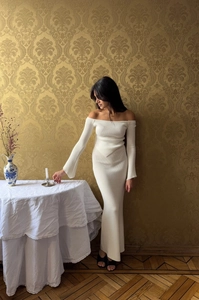 Detail of the white off-shoulder knitted dress texture in a vintage indoor setting