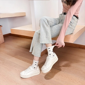 Close-up of white mid-calf socks with black bow patterns and casual white platform shoes