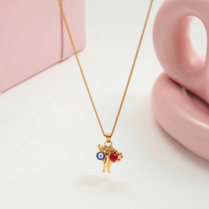 Close-up of evil eye pendant with golden horn and red bead on a fine 18K gold chain