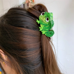 Detail of cute green dinosaur acrylic hair claw clip worn on dark brown hair