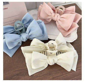 Detailed close-up of blue, pink, and white satin bow hair claws on a vintage plate