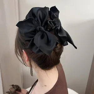 Rückansicht eines Models mit großer schwarzer Satin-Schleife-Haarklammer für Duttfrisuren