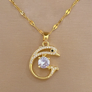 Macro shot of gold dolphin pendant necklace with shimmering crystals and zircon stone