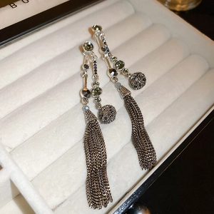 Detail of silver long tassel earrings with olive green and dark grey crystals