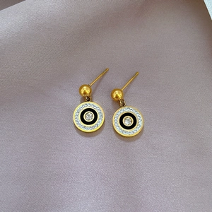 Nahaufnahme goldener Ohrstecker im römischen Stil mit schwarzer Emaille und Kristallen