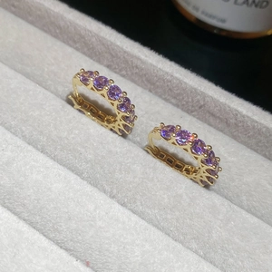 Close-up of vintage style gold earrings with round purple gemstones on a jewelry tray