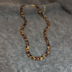 Flachbild der Vintage-Schlangenkette mit Leopardenmuster auf grauem Webpelz-Hintergrund