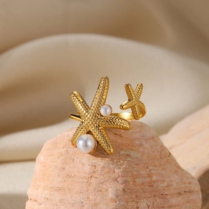 Detail of gold starfish ring with pearls on textured stone and beige fabric backdrop