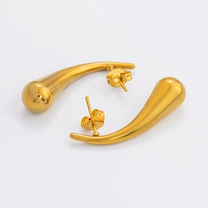 Detail of polished golden teardrop earrings with elegant curved surface and mirror finish