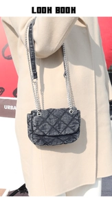 Detail of black denim quilted shoulder bag with silver chain strap on beige coat