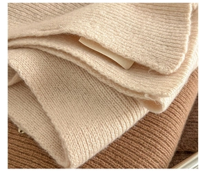 Detailed macro view of the 100% pure wool knit scarf showing soft ribbed texture and label