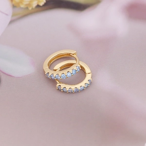 Minimalist 18K gold huggie earrings featuring sparkling light blue zircon stones