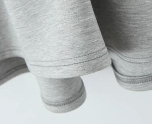 Vue détaillée de l'ourlet de la robe en maille grise avec couture à double aiguille