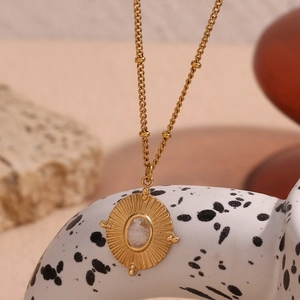 Detailed close-up of 18K gold-plated sunburst pendant with white natural stone necklace
