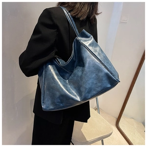 Detailed view of the large navy blue faux leather tote bag worn by a model for size scale