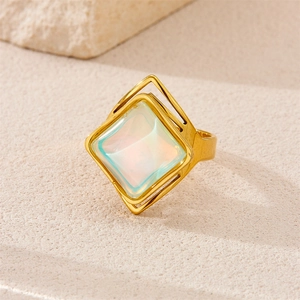 Close-up of vintage 18K gold plated ring with square opal stone on beige stone texture