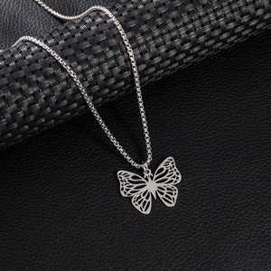 Collier en acier inoxydable argenté avec pendentif papillon sur fond texturé noir