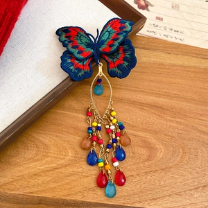 Detailed close-up of embroidered butterfly hair clip with colorful crystal bead tassels