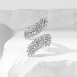 Macro detail of silver leaf bypass ring with cubic zirconia on white rock