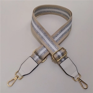 Close-up of adjustable beige shoulder strap with silver glitter stripes and gold hardware