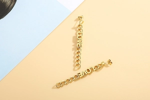 Detail of long gold chain earrings featuring hollow LOVE letters and metallic fringe