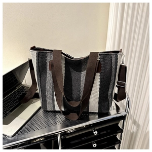 Detail of striped canvas tote bag showing dark brown handles and reinforced leather patches