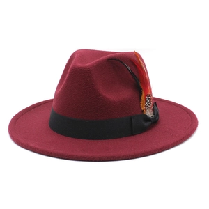 Close-up of burgundy wool felt fedora featuring a black ribbon and colorful feather accent