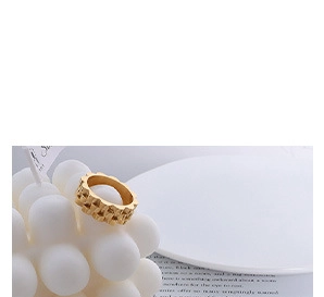 Detail of a geometric faceted gold ring displayed on a white bubble candle background