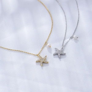 Detailed view of gold and silver starfish necklaces with pearls on white silk background