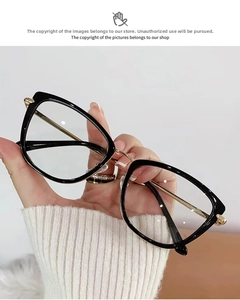 Detail of cat-eye glasses with black frames and gold metal temples held in hand