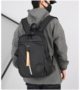 Detail of black large capacity backpack with USB charging port and orange fashion ribbon