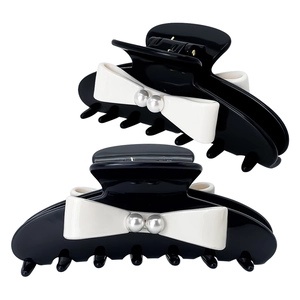 Grande molletta per capelli in acetato nero con fiocco bianco e perle su sfondo bianco