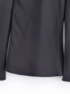 Detailed macro view of the smooth black fabric texture and flat hem stitching on the top