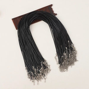 Macro shot of bulk black wax necklace cords with silver lobster clasps on a wood stand
