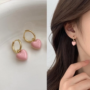 Detail of pink heart dangle earrings featuring golden hoops and a model wearing the jewelry