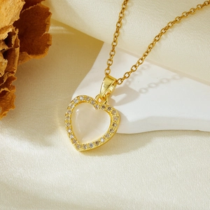 Close-up of golden heart pendant with cat eye stone and zircon crystals on silk fabric